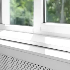 Białe parapety wewnętrzne zamontowane nad grzejnikiem. Słońce pięknie oświetla gładką powierzchnię.