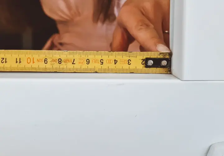 Dłoń z miarką pokazuje, jak zmierzyć okno do moskitiery. Miarka wskazuje ok. 10 cm.