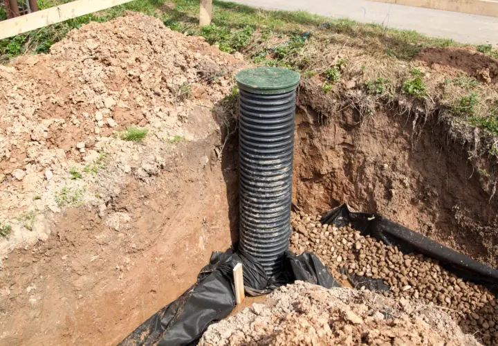 Wykop pod rów melioracyjny z rurą drenarską i żwirem. Jaka rura do rowu melioracyjnego? Ta karbowana, czarna rura z zieloną pokrywą jest gotowa do pracy.